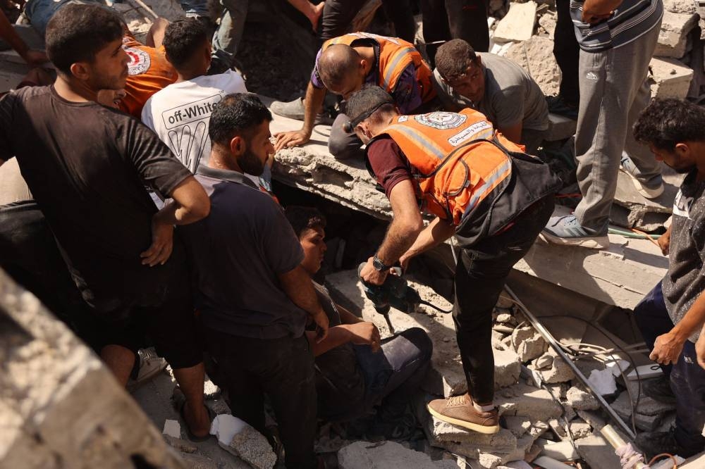 Palestinians search for survivors amid the rubble of a building, which collapsed after Israeli bombardment on a building adjacent to it, in the Sheikh Radwan neighbourhood in Gaza City, on Monday. AFP