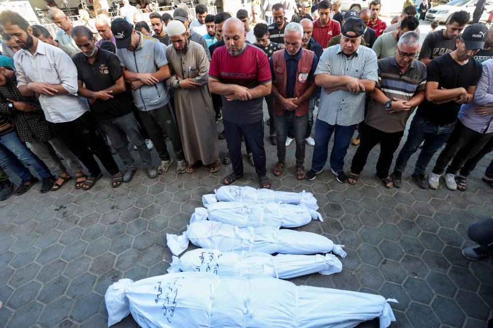 Mourners pray next to the bodies of Palestinians killed in Israeli strikes at Al-Aqsa Martyrs Hospital in Deir Al-Balah in the central Gaza Strip, on Monday. REUTERS
