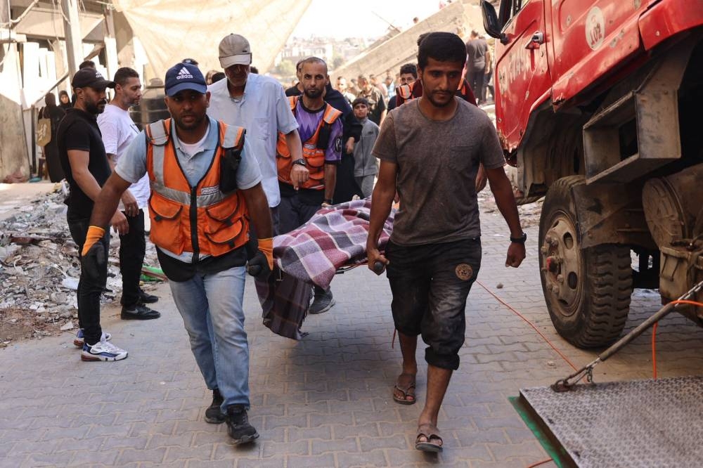 Palestinians evacuate a body, retrieved from the rubble of a building, which collapsed after Israeli bombardment on a building adjacent to it, in the Sheikh Radwan neighbourhood in Gaza City, on Monday. AFP