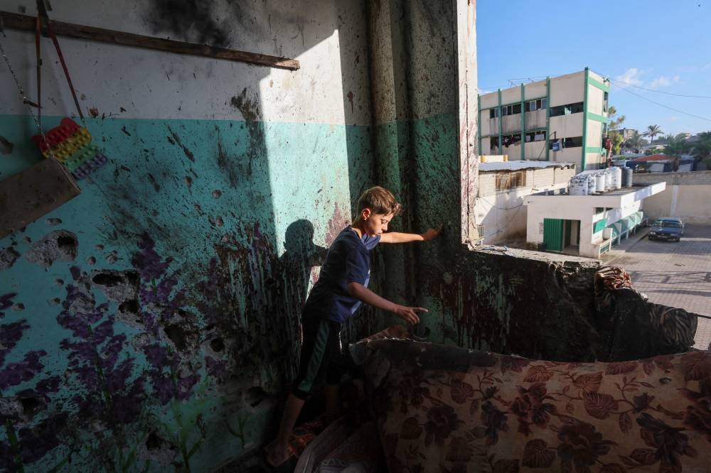 A Palestinian child inspects the damage inside a school sheltering displaced people after it was hit by an Israeli strike, on Monday. REUTERS