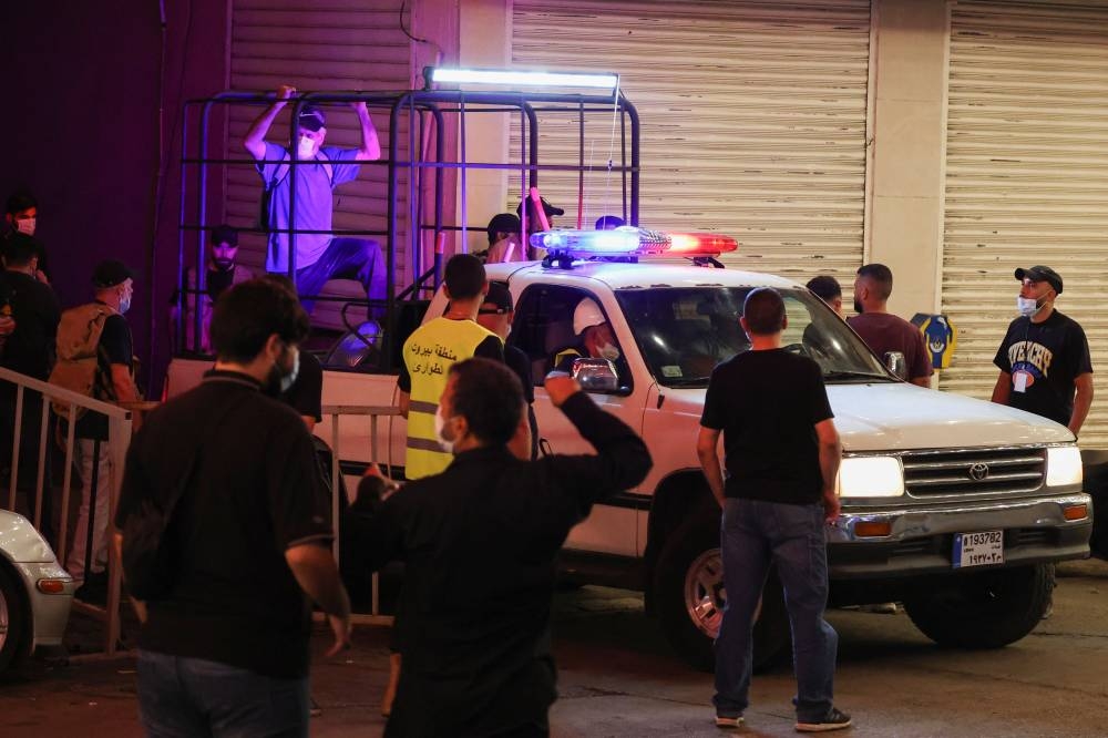 A vehicle moves as people gather near the site of an Israeli strike in Beirut's southern suburbs, Lebanon on Monday. REUTERS