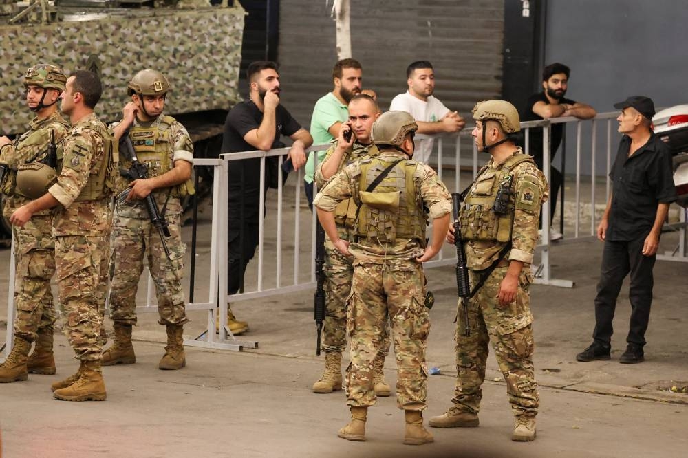 Members of Lebanese Army stand as people gather near the site of an Israeli strike in Beirut's southern suburbs, Lebanon on Monday. REUTERS