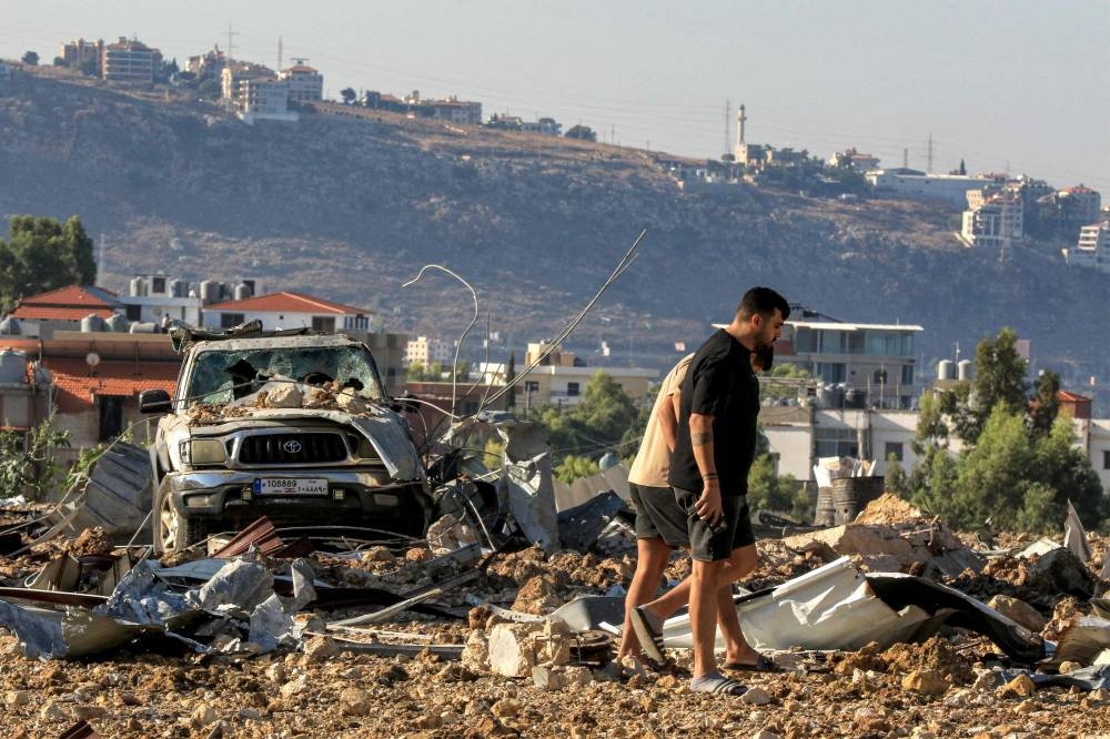 People inspect the site of an Israeli air strike in Jiyeh along the highway linking Beirut to the southern city of Sidon on Wednesday. AFP