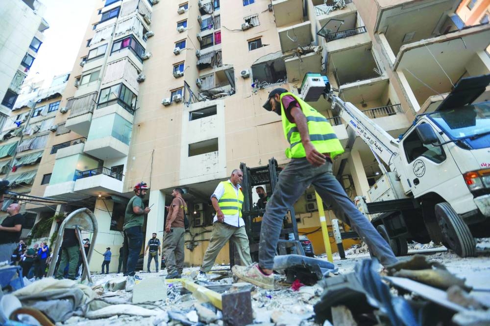People and rescuers gather at the site of an Israeli airstrike that targeted an apartment on Al-Qaem street in Beirut’s southern suburbs on Thursday 
