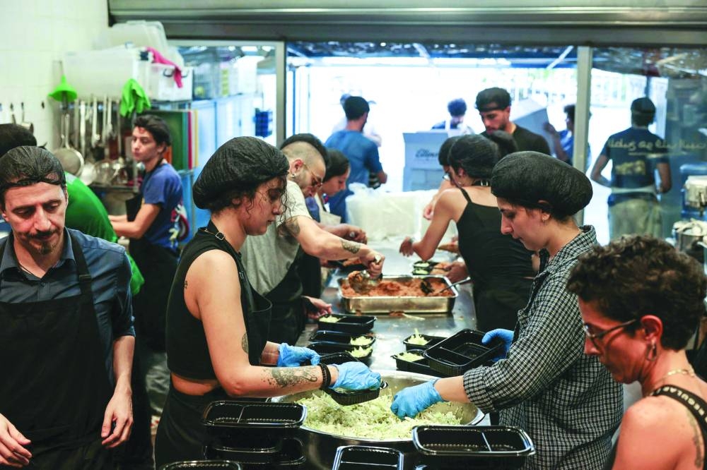 Volunteers work in a community kitchen to prepare meals for those who fled Israeli bombardment in southern Lebanon and found refuge in temporary shelters in Beirut, on Thursday 