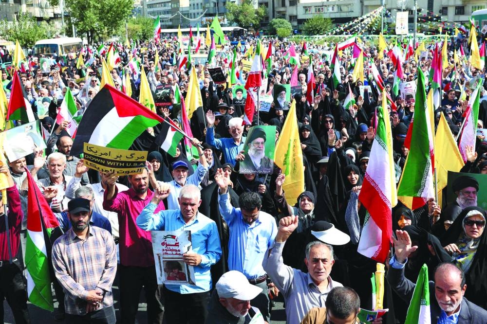 
Iranians raise their national flag as well as Palestinian and Lebanon’s Hezbollah flags during an anti-Israel protest in Tehran, yesterday. 
