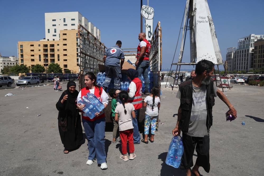 Displaced families receive water and food after fleeing the overnight Israeli strikes, amid ongoing hostilities between Hezbollah and Israeli forces, in southern Beirut, in Lebanon on Saturday. REUTERS