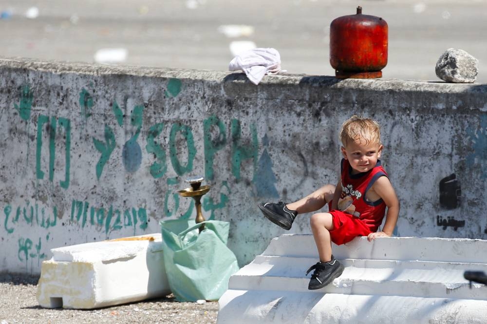 A child sits on a street as displaced families stay on the roads after spending the night fleeing the overnight Israeli strikes in southern Beirut, in Lebanon on Saturday. REUTERS