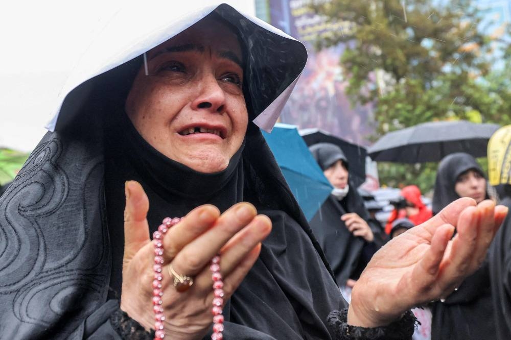 A woman reacts while holding her hands out in prayer during an anti-Israel protest in Tehran's Palestine Square on Saturday. AFP