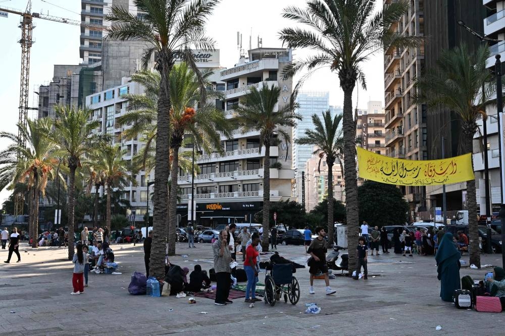 People who fled Israeli bombardment on Beirut's southern suburbs, gather along the Lebanese capital's seaside corniche where they spent the night, on Saturday. AFP