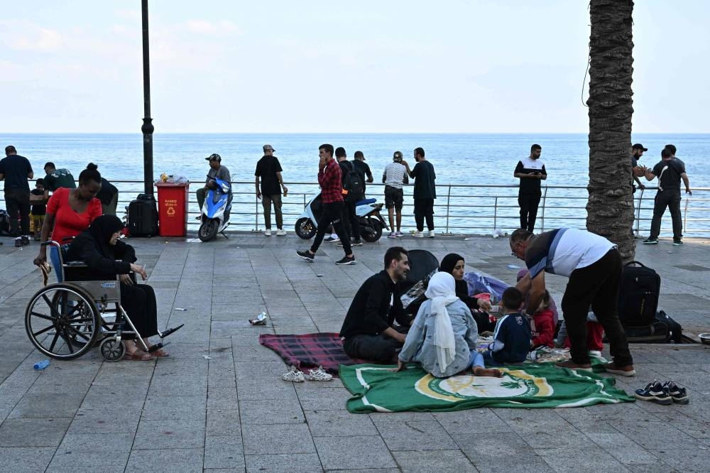 People who fled Israeli bombardment on Beirut's southern suburbs, gather along the Lebanese capital's seaside corniche where they spent the night, on Saturday. AFP