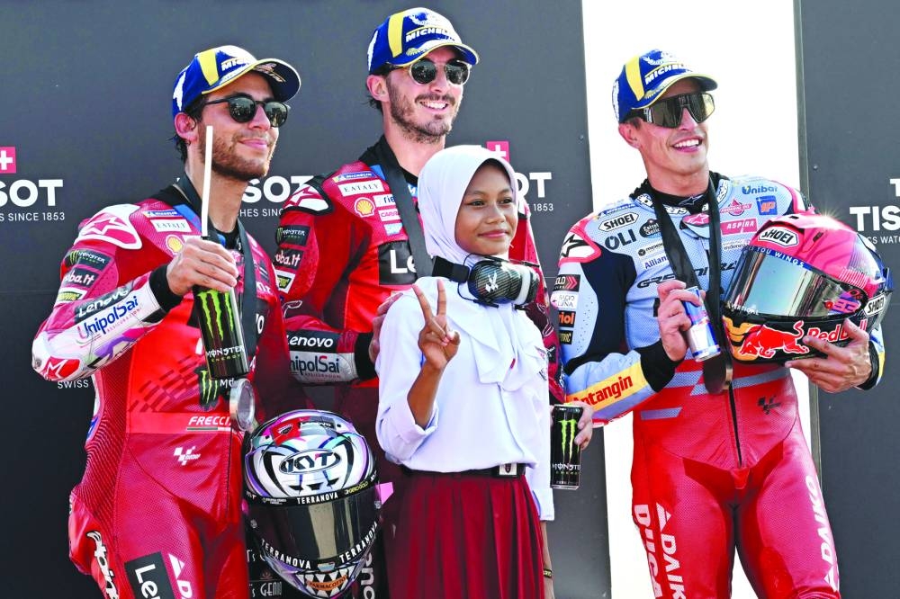 FROM LEFT: Second-placed Ducati Lenovo Team’s Italian rider Enea Bastianini, first-placed Ducati Lenovo Team’s Italian rider Francesco Bagnaia, and third-placed Gresini Racing MotoGP’s Spanish rider Marc Marquez pose with a schoolgirl on the podium following the MotoGP sprint race of the Indonesian Grand Prix at the Mandalika International Circuit in Mandalika, West Nusa Tenggara, on Saturday. (AFP)