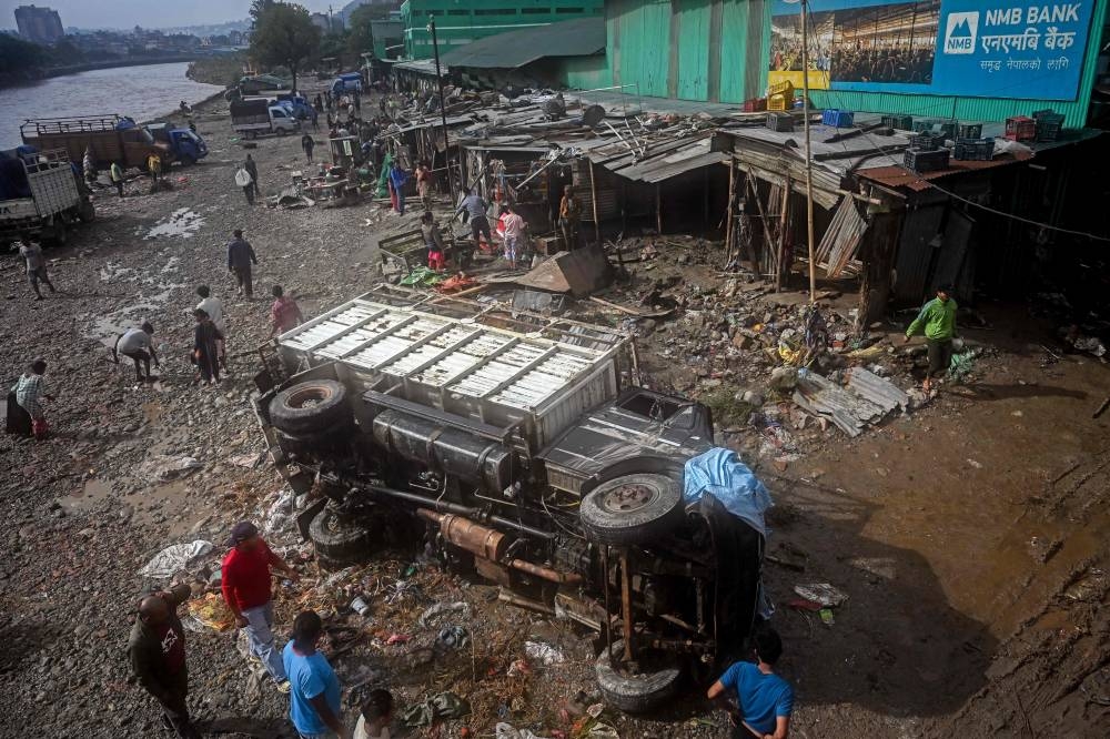 A damaged vehicle is seen amid mud and debris in a flood-affected area following heavy monsoon rains in Kathmandu on Sunday, AFP
