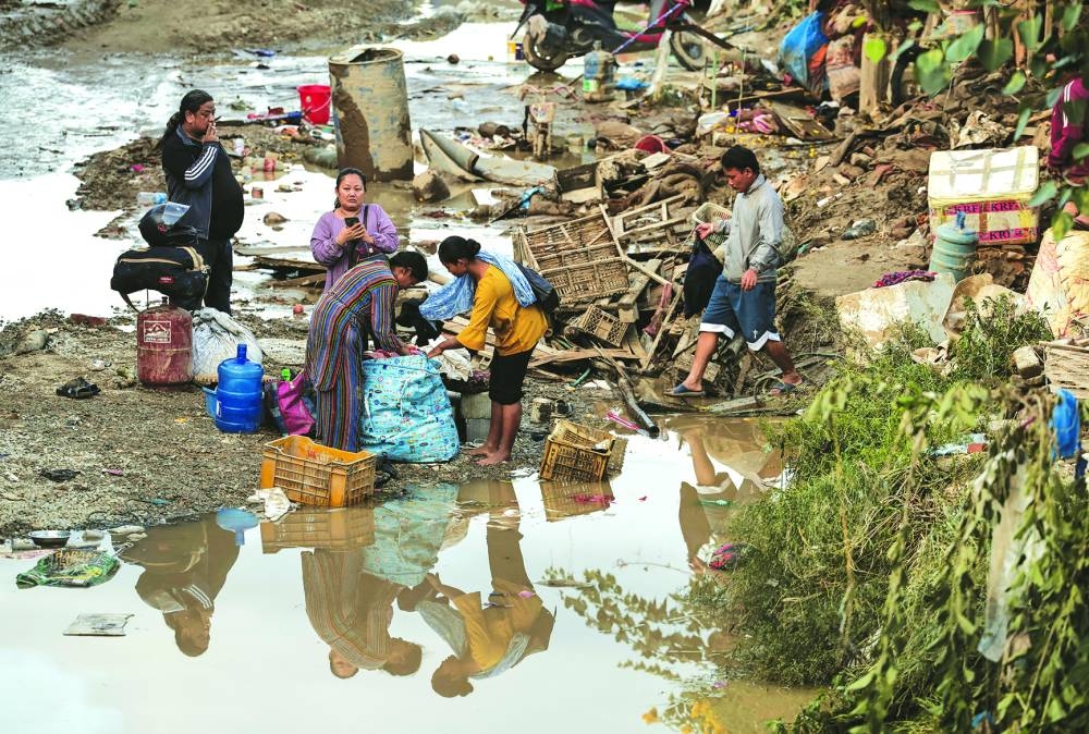 
People salvage their belongings along a street as the floodwater recedes in an area that was flooded by the overflowing Bagmati River following heavy rains in Kathmandu, Nepal, yesterday. 