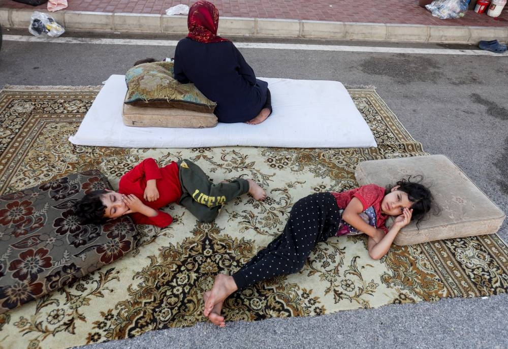 Syrian refugees, who fled from southern Lebanon villages due to ongoing hostilities between Hezbollah and Israeli forces, take shelter in a parking lot in Sidon, Lebanon on Monday. REUTERS