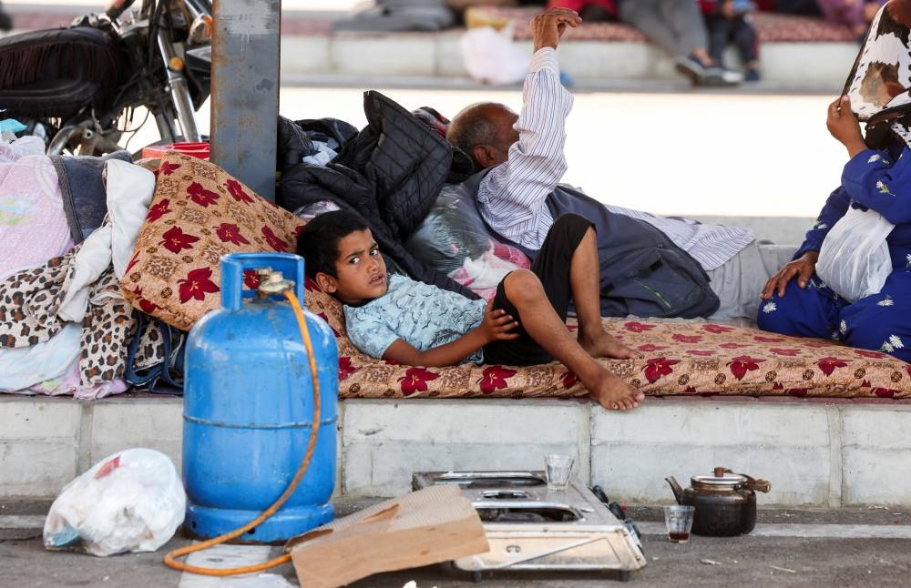 Syrian refugees, who fled from southern Lebanon villages due to ongoing hostilities between Hezbollah and Israeli forces, take shelter in a parking lot in Sidon, Lebanon Monday. REUTERS