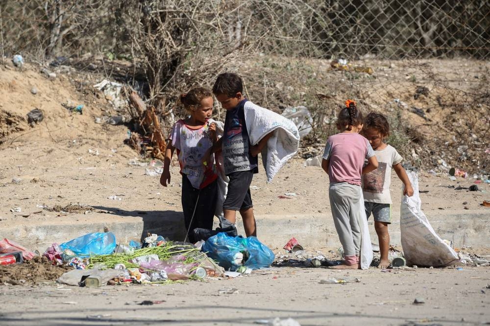Palestinian children salvage items from garbage in Deir el-Balah in the central Gaza Strip on Monday. AFP