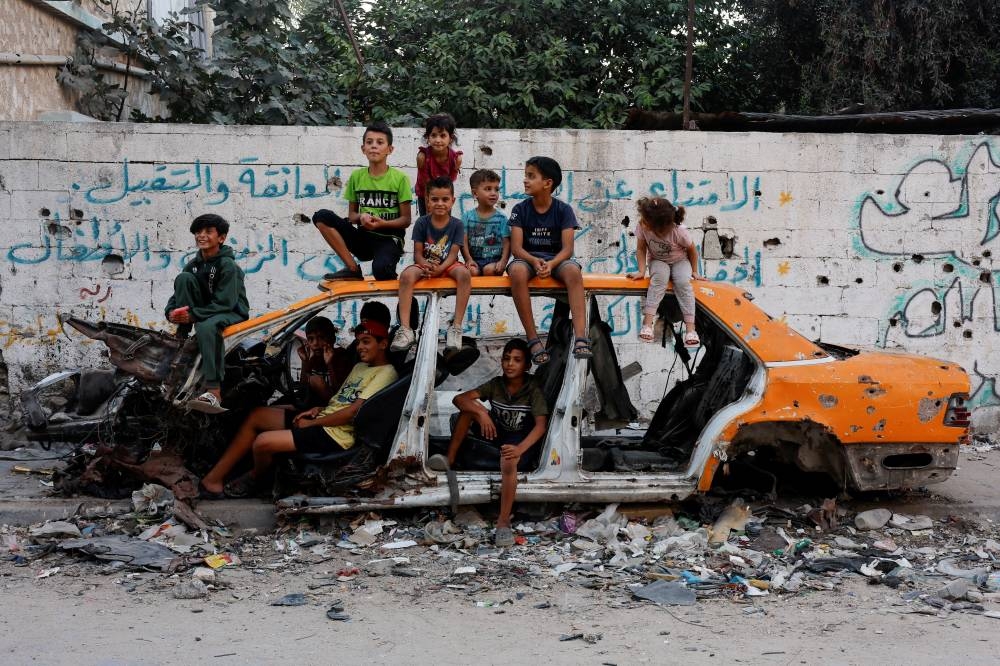 Palestinian children gather at a destroyed vehicle, amid the Israel-Hamas conflict, in Khan Younis in the southern Gaza Strip, on Monday. REUTERS