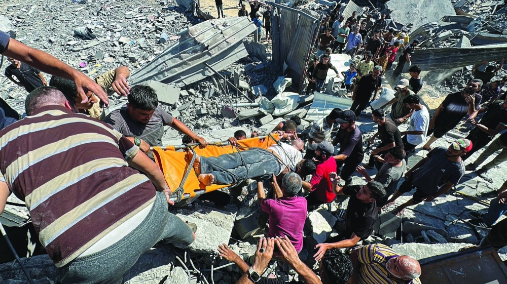 Palestinians carry a wounded man at the site of an Israeli strike in Nuseirat in the central Gaza Strip Monday.