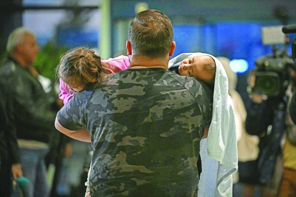 A man carries two children after arriving at Sofia airport on an evacuation flight from Lebanon, Monday.