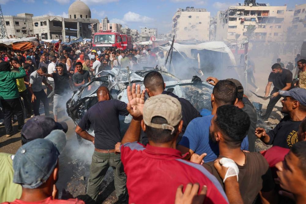 Displaced Palestinians douse a burning car with water after it was hit in an Israeli strike in Khan Yunis in the southern Gaza Strip city on Tuesday. AFP