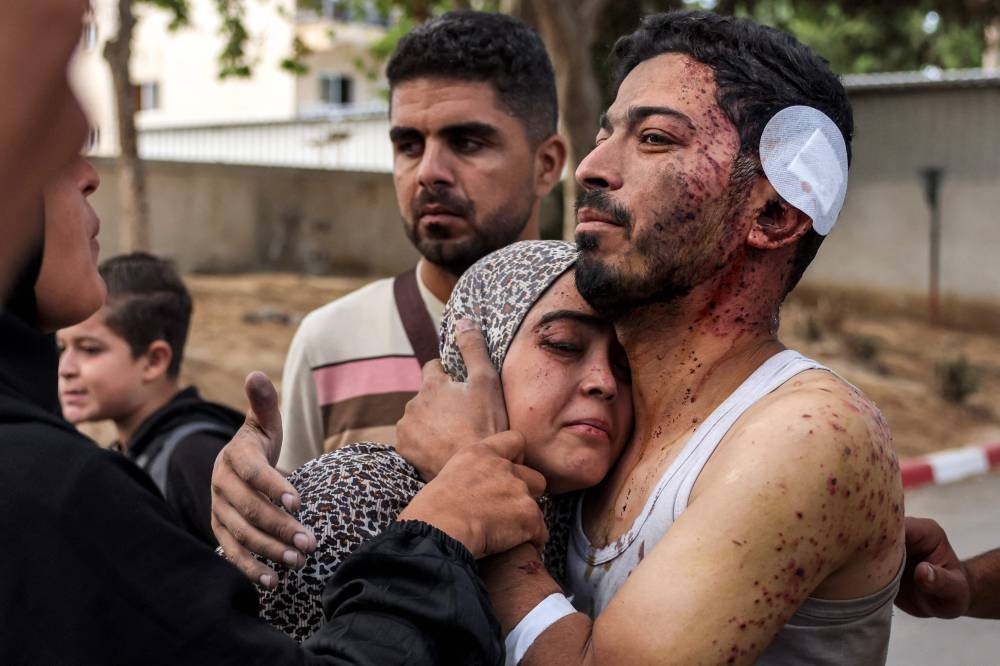 An injured man comforts a woman during a funeral for victims killed in Israeli bombardment in Khan Yunis in the southern Gaza Strip on Wednesday. AFP