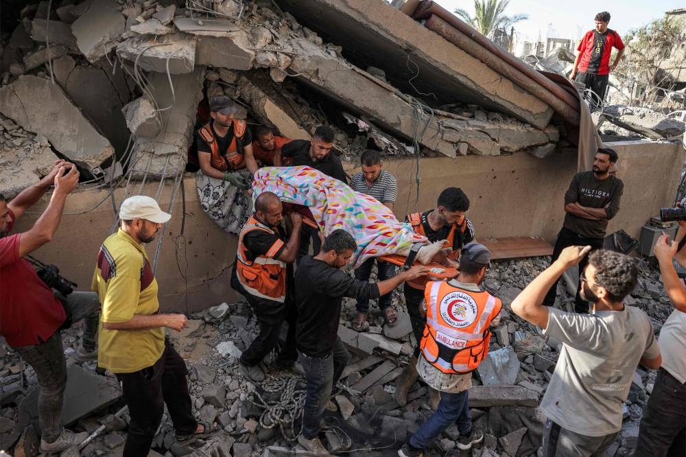 Palestinian Civil Defence rescuers extract the body of a victim from a hole underneath the rubble of a collapsed building in Khan Yunis in the southern Gaza Strip on Wednesday. AFP