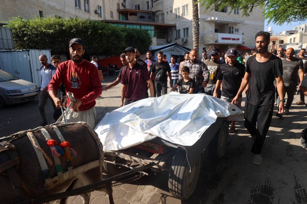 Palestinians transport the bodies of people killed in a house hit by an Israeli strike, from a hospital in Deir El-Balah in the central Gaza Strip on Friday. AFP