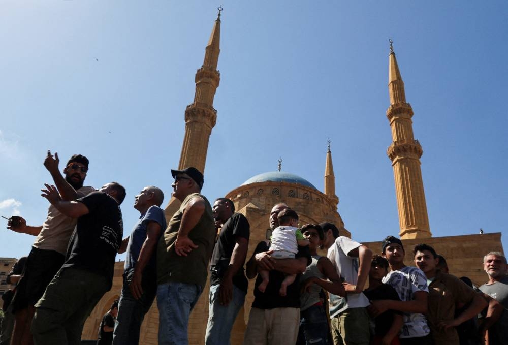 Displaced families, after fleeing the overnight Israeli strikes, queue to receive vegetable soup from a mobile "soup station" set up by a charity organisation "Caritas Christian Charity" for the displaced people unable to find shelter in official centres,  in front of Mohammad Al-Amin mosque at Beirut's central Martyrs' Square in Lebanon, on Thursday. REUTERS