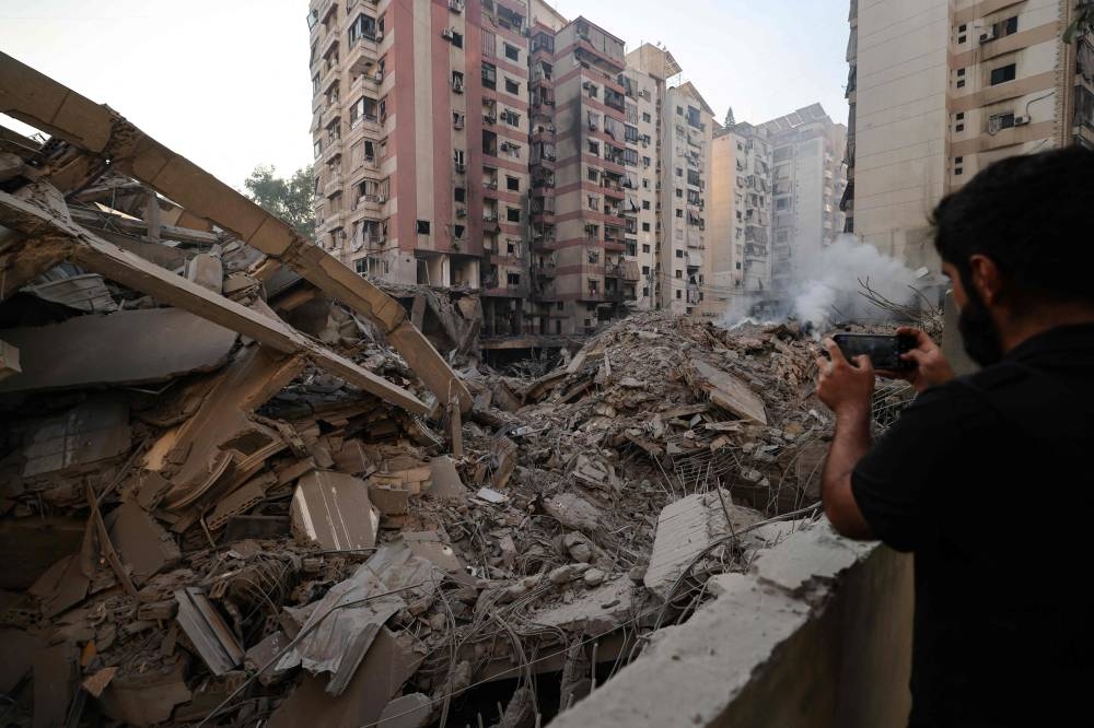 A man photographs the rubble of a building levelled by an Israeli airstrike that targeted Beirut’s southern suburbs, on Saturday. AFP