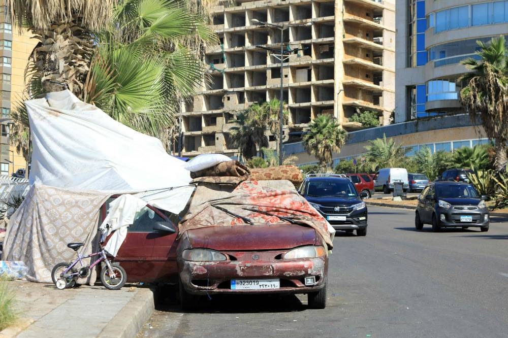A car is used as part of a temporary shelter installed by people who fled Israeli bombing and took refuge in Beirut's seaside Rawsheh area, on Saturday. AFP