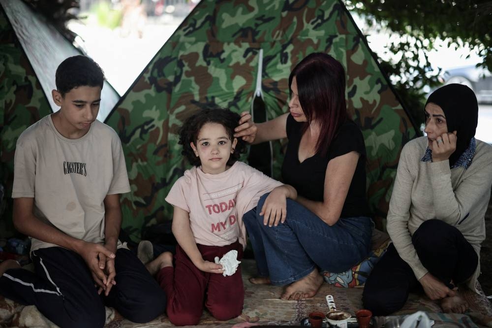 Dallas Eissa attends to her sick daughter, Zeinab by their makeshift shelter, along a seaside in western Beirut, Lebanon, on Sunday. REUTERS