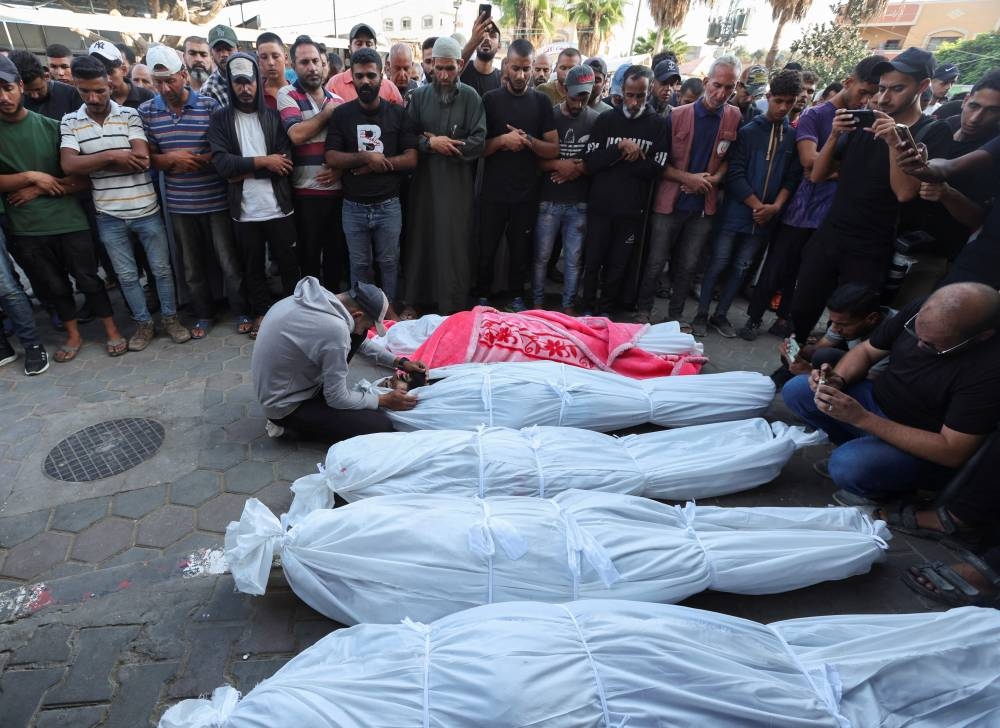 Mourners pray next to the bodies of Palestinians, who were killed in an Israeli strike at Al-Aqsa Martyrs Hospital in Deir Al-Balah in the central Gaza Strip, on Sunday. REUTERS
