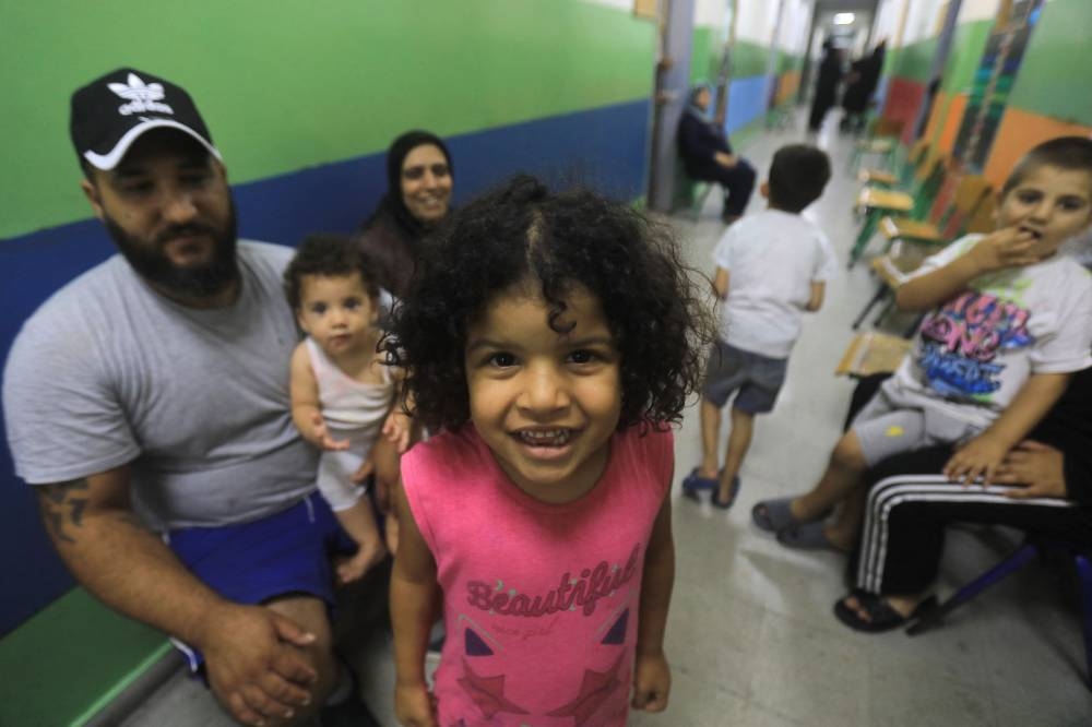 A father plays with his children in the corridor at a school, housing families displaced from the south of Lebanon, in Beirut on Saturday. AFP