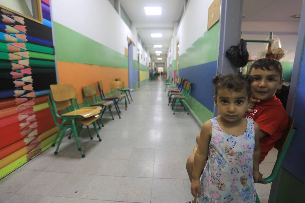 Children pose for a picture in the corridor at a school, housing families displaced from the south of Lebanon, in Beirut on Saturday. AFP