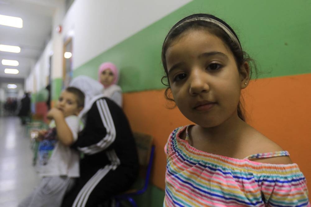 Children pose for a picture in the corridor at a school, housing families displaced from the south of Lebanon, in Beirut on Saturday. AFP
