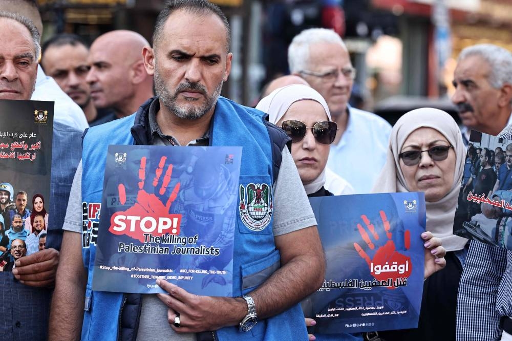 Protesters carry posters bearing pictures of slain Palestinian journalists during a rally to condemn their killing, in Ramallah in the occupied West Bank, on Sunday. AFP