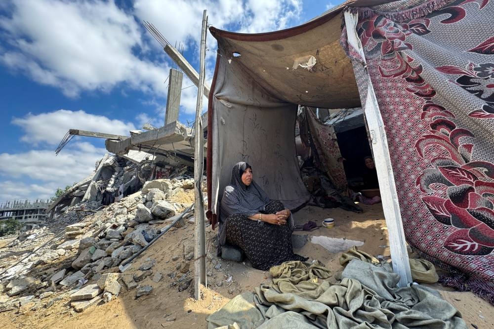 A Palestinian woman sits in a makeshift tent next to rubble of a house destroyed in Israel's military offensive, in Khan Younis in the southern Gaza Strip on Monday. REUTERS