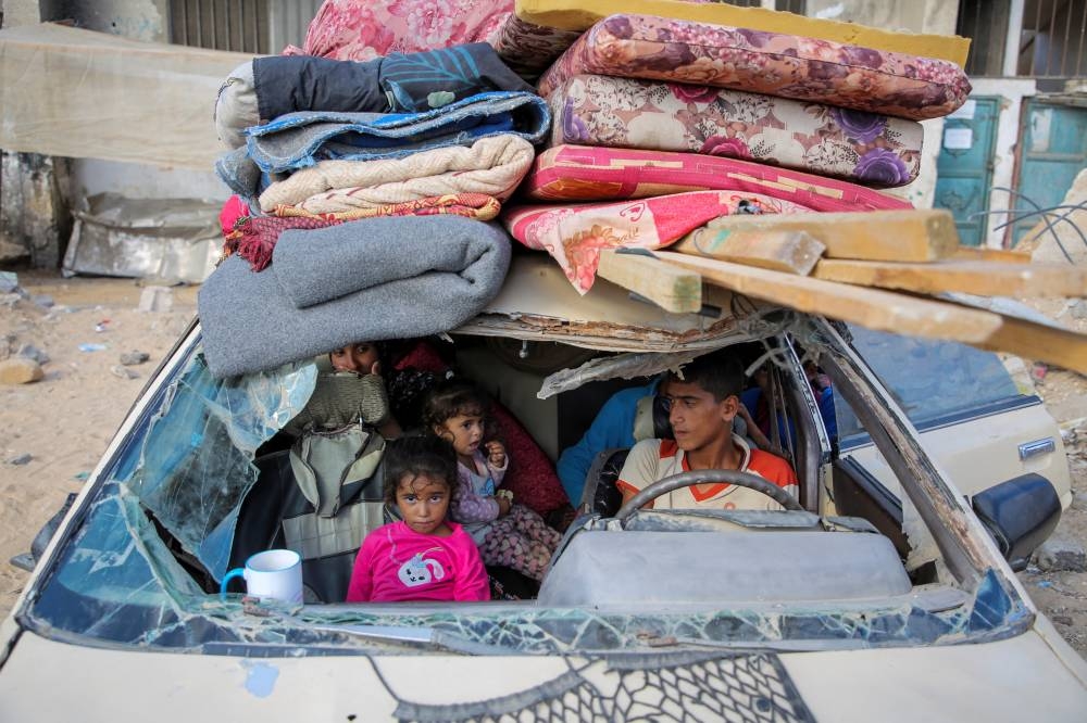 Displaced Palestinian children sit in a damaged car as they flee areas in the eastern part of Khan Younis following an Israeli evacuation order, in Khan Younis in the southern Gaza Strip, on Monday. REUTERS