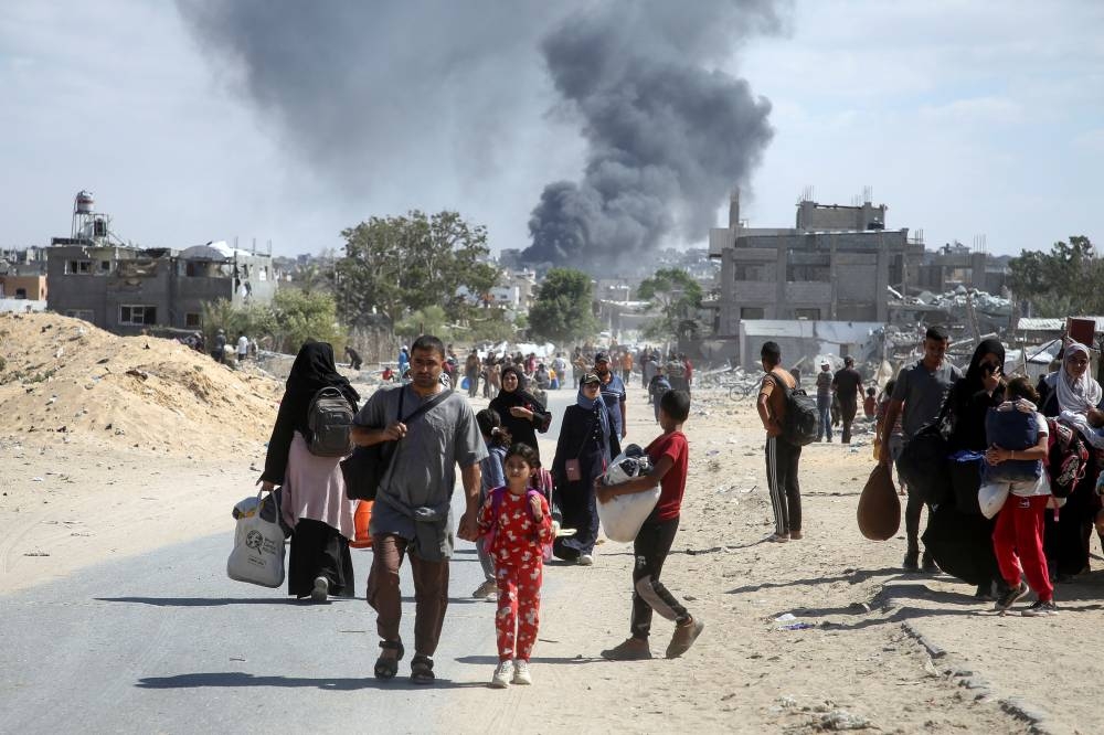 Smoke rises following an Israeli strike as displaced Palestinians make their way to flee areas in the eastern part of Khan Younis following an Israeli evacuation order, in Khan Younis in the southern Gaza Strip, on Monday. REUTERS