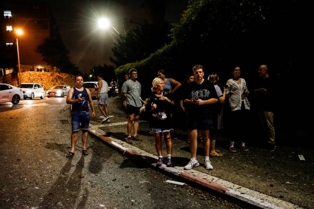 People look on after a projectile fell, in Haifa, northern Israel, on Monday. REUTERS