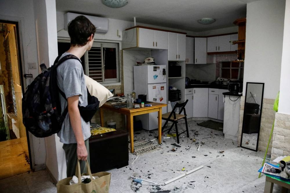 A person stands near debris inside a building after a projectile fell, in Haifa, northern Israel, on Monday. REUTERS