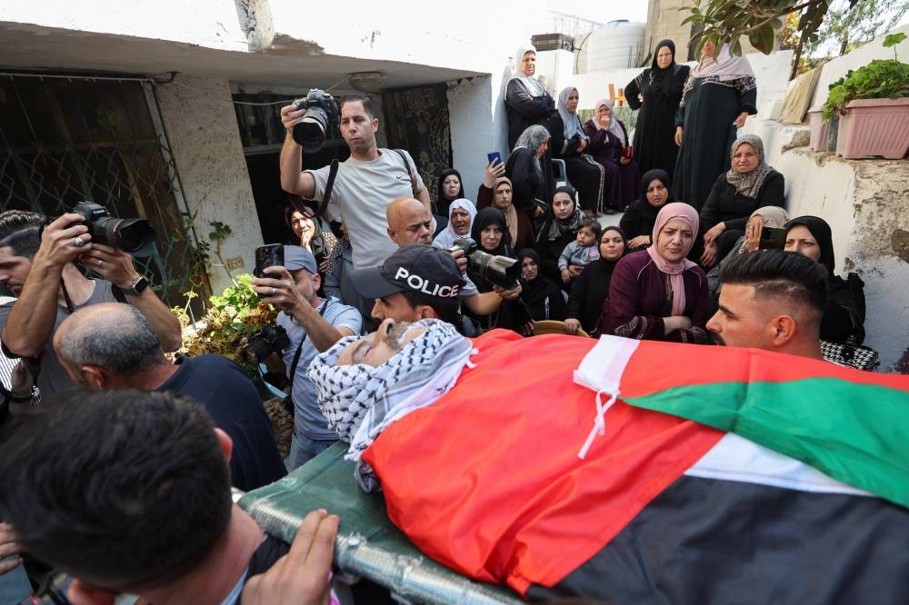 Mourners carry the body of Palestinian elderly Ziad Abu Hlail who was killed in an Israeli raid, during his funeral in Dura in the Israeli-occupied West Bank, on Monday. REUTERS