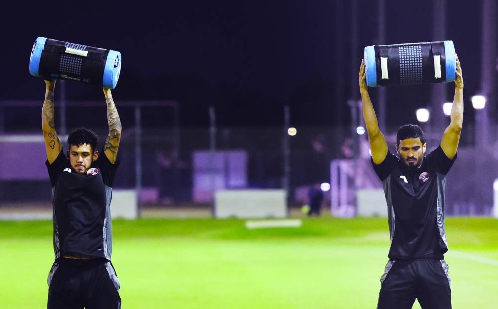 Qatar’s Abdelkarim Hassan (centre) and teammate Akram Afif (right) during a training session in Doha on Monday. Asian champions Qatar, coached by Marquez Lopez of Spain, take on Kyrgyzstan in a 2026 FIFA World Cup qualifying match at Al Thumama Stadium in Doha on Thursday. Qatar players undergo stretching exercises during a training session at Aspire Academy in Doha.