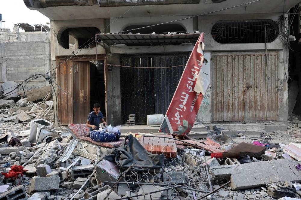 A Palestinian youth collects salvaged items following an Israeli air strike the previous night on the Bureij refugee camp in the central Gaza Strip on Tuesday. AFP