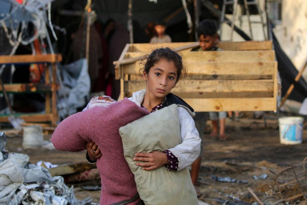 A child carries salvaged items following an Israeli air strike the previous night on the Bureij refugee camp in the central Gaza Strip on Tuesday. AFP