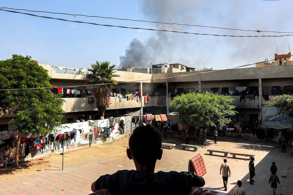 A boy watches a smoke plume rise while standing in the balcony of the Rafei school, being used as a displacement shelter, in the Jabalia camp for Palestinian refugees in the northern Gaza Strip on Wednesday. AFP
