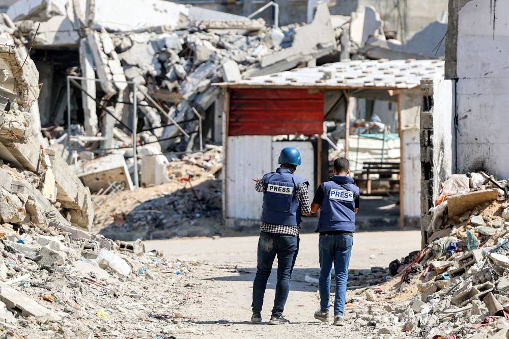 Journalists film while standing before destroyed buildings in the Jabalia camp for Palestinian refugees in the northern Gaza Strip on Wednesday. AFP