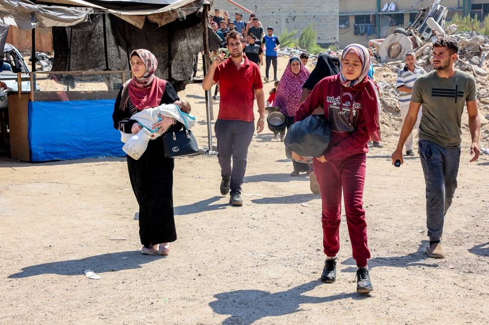 Evacuating people walk with belongings in the Jabalia camp for Palestinian refugees in the northern Gaza Strip on Wednesday. AFP