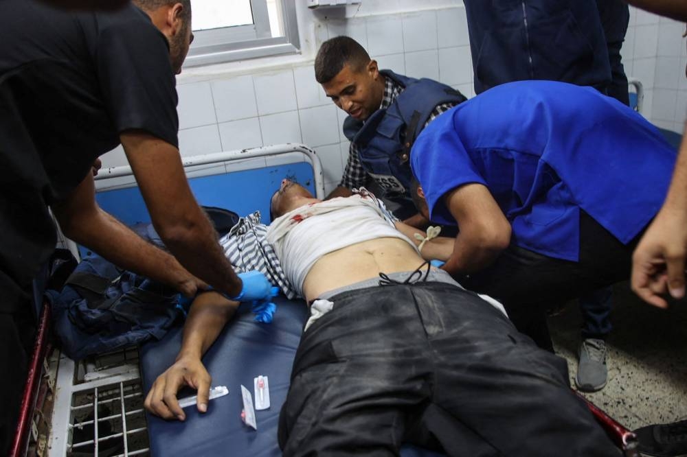 Medics and colleagues of Al Jazeera photojournalist Fadi al-Wahidi, who was reportedly shot by Israeli troops while reporting in the northern Gaza Strip, stand next to him as he receives treatment at Al-Ahli Arab hospital, Wednesday. REUTERS